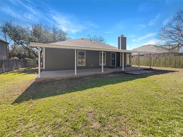 back of property featuring a yard, a chimney, a patio area, and a fenced backyard