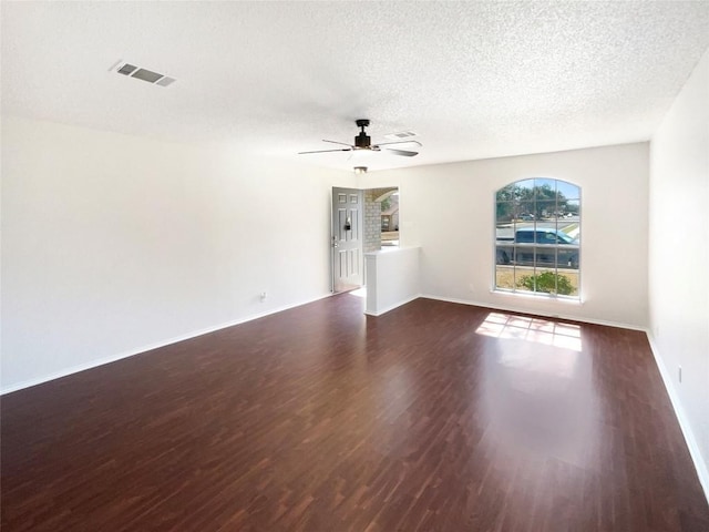 unfurnished living room featuring dark wood-style flooring, visible vents, a ceiling fan, a textured ceiling, and baseboards