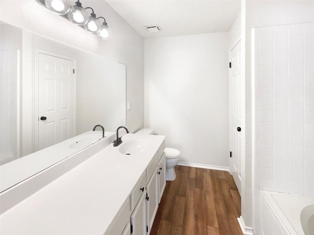 bathroom with baseboards, visible vents, toilet, wood finished floors, and vanity