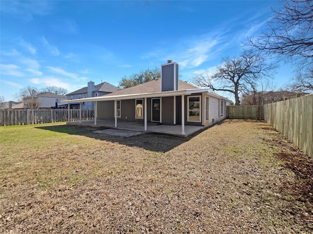 rear view of property with a patio area, a fenced backyard, a chimney, and a lawn