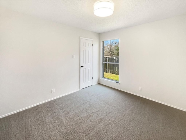 unfurnished room featuring baseboards, dark carpet, and a textured ceiling