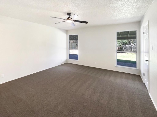 empty room featuring dark carpet, a textured ceiling, baseboards, and ceiling fan