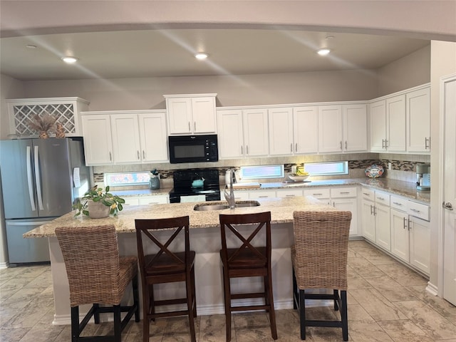 kitchen featuring black appliances, backsplash, a sink, and white cabinetry