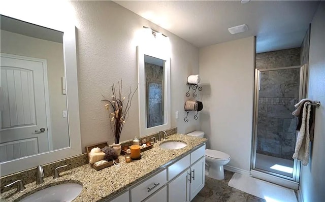 bathroom featuring a stall shower, a sink, toilet, and double vanity