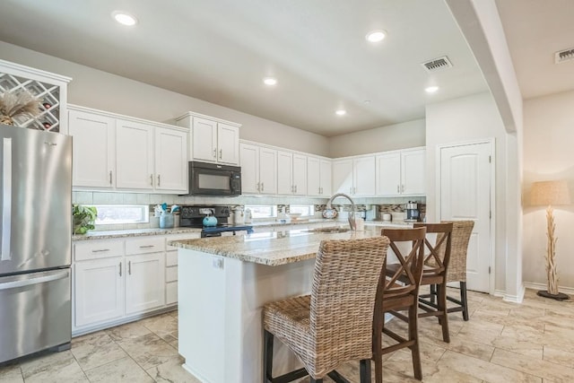 205 Birch Oak Ln, Georgetown, TX 78628 - kitchen with a breakfast bar area, visible vents, white cabinetry, backsplash, and black appliances