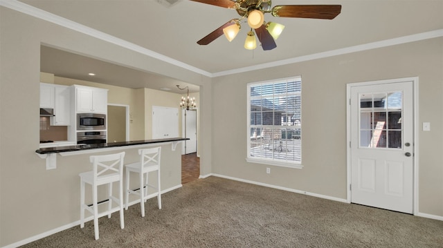 kitchen featuring a breakfast bar, dark countertops, ornamental molding, and stainless steel appliances