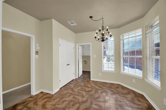 unfurnished dining area featuring baseboards, visible vents, and a notable chandelier