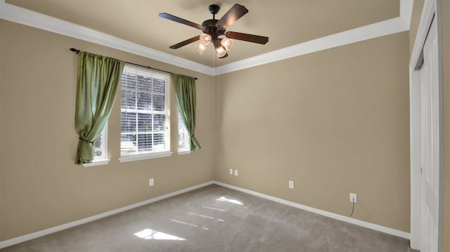 empty room with ornamental molding, carpet flooring, a ceiling fan, and baseboards