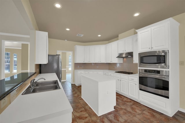 kitchen with visible vents, a sink, stainless steel appliances, under cabinet range hood, and backsplash