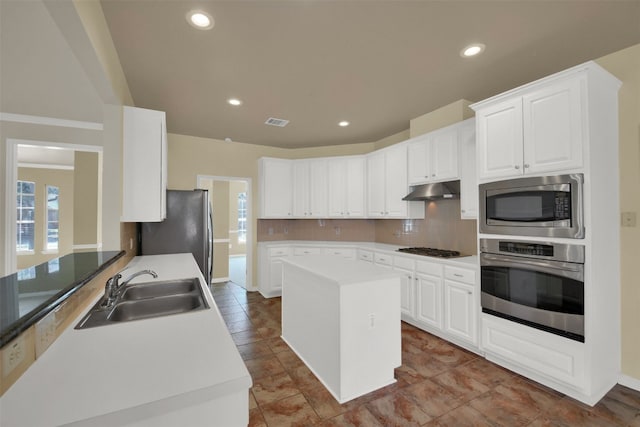 kitchen with under cabinet range hood, visible vents, a sink, tasteful backsplash, and appliances with stainless steel finishes