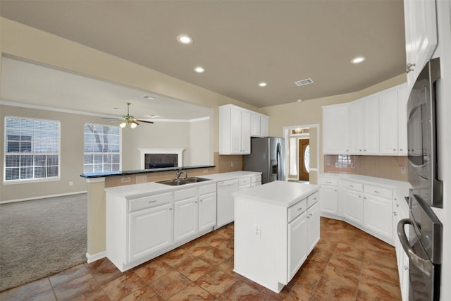 kitchen with a sink, stainless steel refrigerator with ice dispenser, visible vents, white dishwasher, and a kitchen island