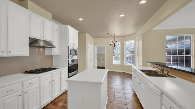 kitchen with a sink, a chandelier, stainless steel appliances, under cabinet range hood, and decorative backsplash