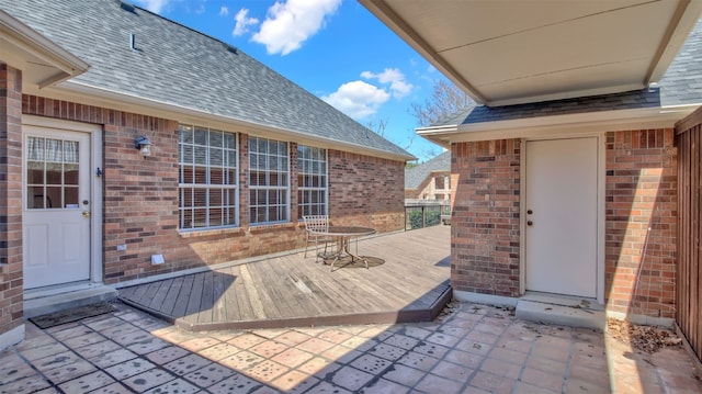 exterior space with a wooden deck, brick siding, and a shingled roof