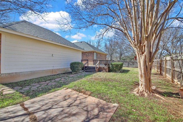 view of yard with a patio, a wooden deck, and a fenced backyard