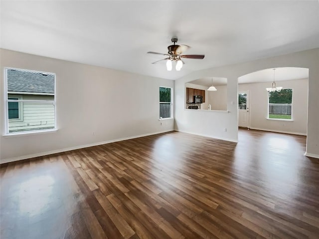 12804 Sago Palm Trl, Elgin, TX 78621 - unfurnished living room with dark wood-style flooring, arched walkways, ceiling fan, and a chandelier