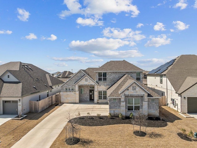 french country inspired facade featuring driveway, stone siding, a residential view, roof with shingles, and fence