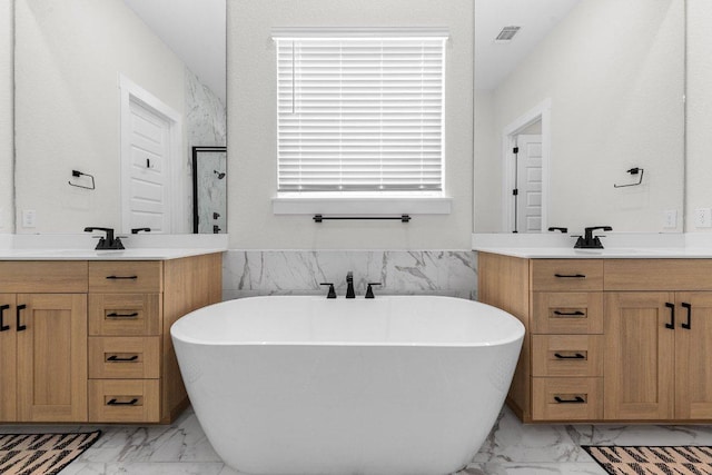 bathroom with a freestanding tub, a sink, two vanities, visible vents, and marble finish floor