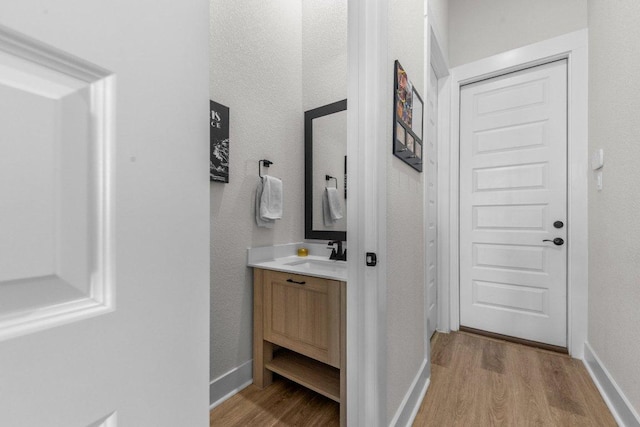 hall with a sink, light wood-style flooring, and baseboards