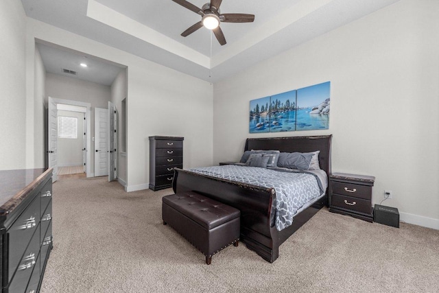 bedroom with baseboards, a tray ceiling, and light colored carpet