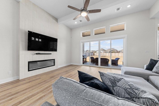 living room featuring visible vents, a ceiling fan, light wood-type flooring, baseboards, and a tile fireplace