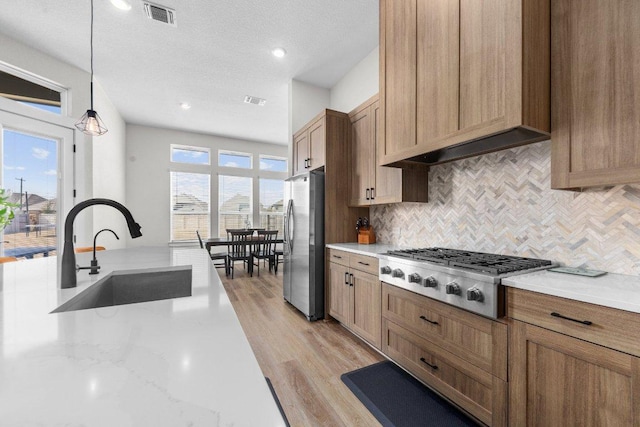 kitchen featuring stainless steel appliances, a sink, visible vents, a wealth of natural light, and decorative backsplash