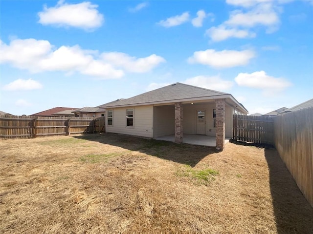 rear view of property featuring a patio area, a yard, a fenced backyard, and roof with shingles