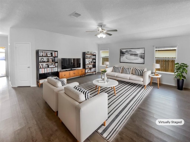 living room featuring visible vents, a textured ceiling, wood finished floors, and a wealth of natural light