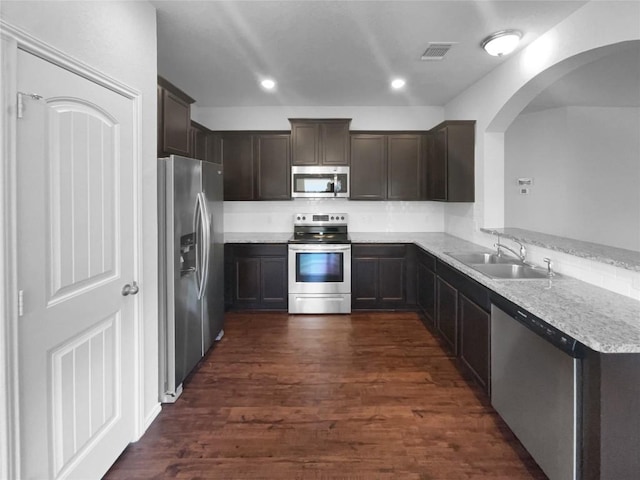 kitchen featuring dark brown cabinetry, dark wood-type flooring, stainless steel appliances, and a sink