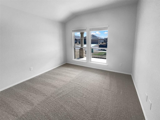 carpeted spare room with lofted ceiling and baseboards