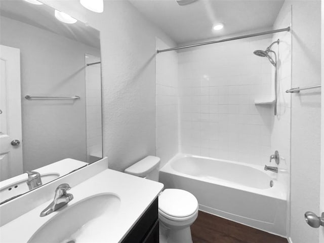 full bathroom with a textured wall, toilet, vanity, wood finished floors, and  shower combination