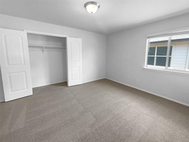 unfurnished bedroom featuring a textured ceiling, a closet, baseboards, and carpet flooring