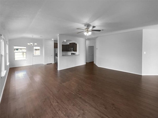 unfurnished living room featuring baseboards, vaulted ceiling, dark wood-type flooring, and ceiling fan with notable chandelier