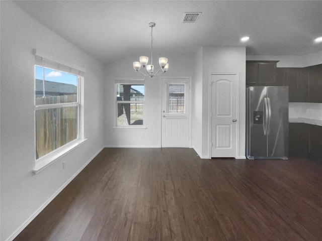 unfurnished dining area featuring visible vents, baseboards, vaulted ceiling, dark wood finished floors, and an inviting chandelier