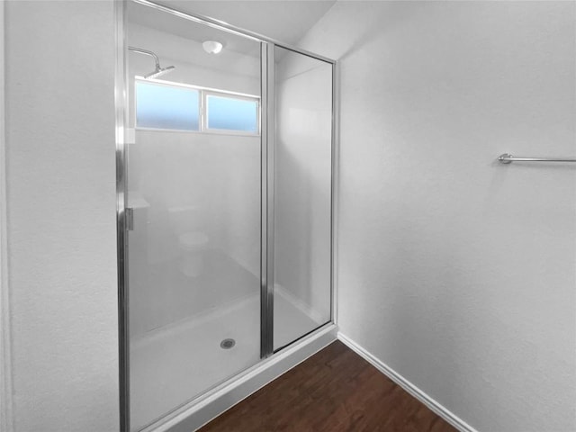 full bathroom featuring a stall shower, wood finished floors, and baseboards