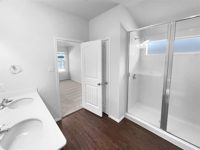 full bathroom with a stall shower, baseboards, a sink, and wood finished floors