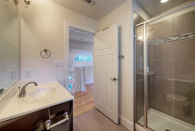 bathroom with a stall shower, tile patterned flooring, visible vents, and vanity