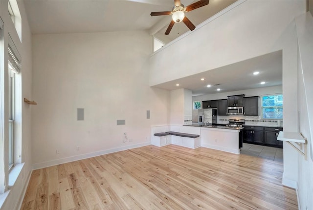 kitchen with stainless steel appliances, open floor plan, a peninsula, and light wood finished floors