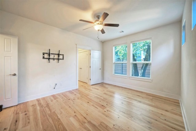 empty room featuring baseboards, visible vents, ceiling fan, and wood finished floors