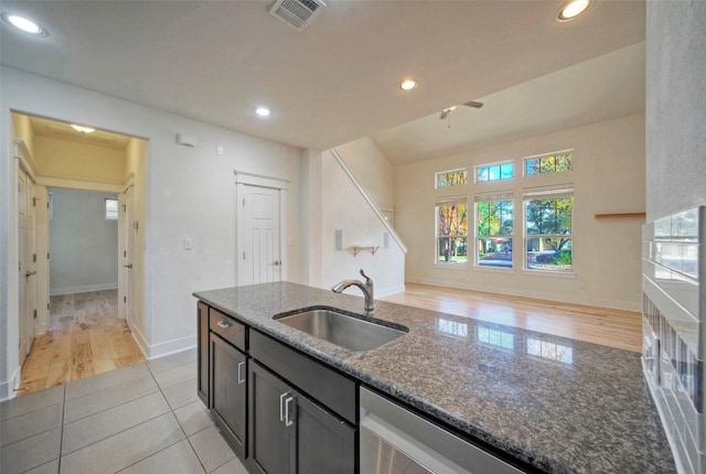 kitchen featuring light tile patterned floors, recessed lighting, visible vents, a sink, and dark stone countertops