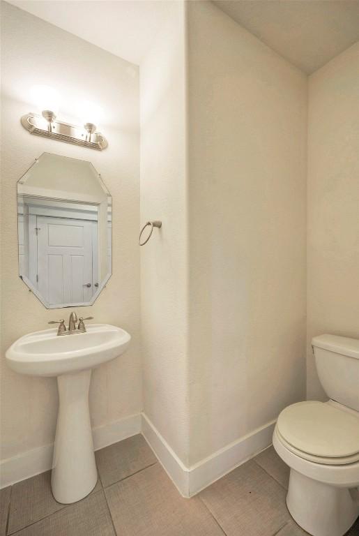 bathroom with baseboards, toilet, and tile patterned floors