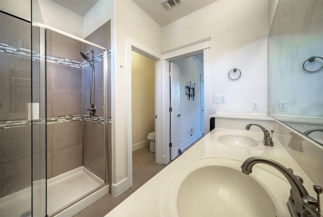 full bathroom featuring toilet, a shower stall, visible vents, and a sink