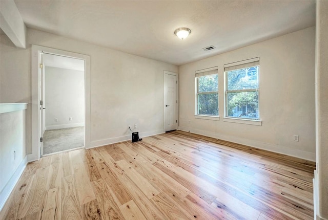 spare room with baseboards, visible vents, and wood finished floors