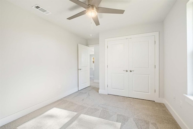 unfurnished bedroom with light colored carpet, a closet, visible vents, and baseboards