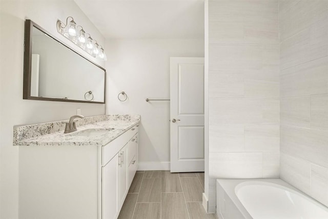 full bathroom featuring a bathing tub, baseboards, and vanity