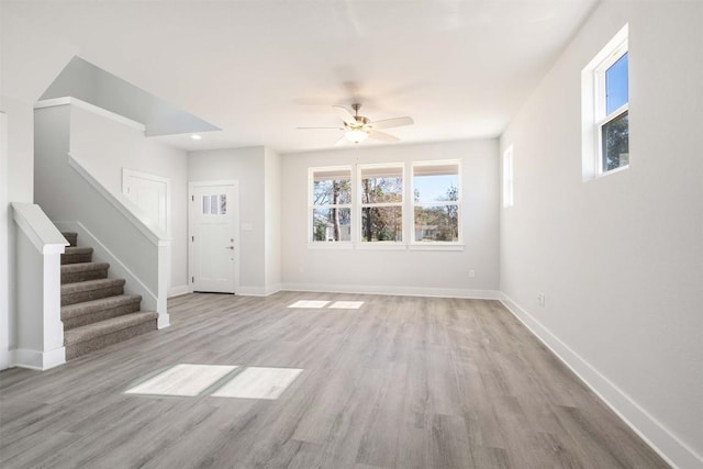 unfurnished living room featuring light wood finished floors, ceiling fan, stairs, and baseboards