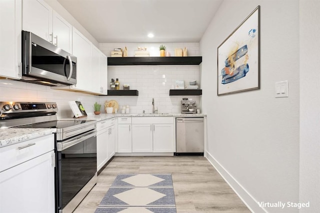 kitchen with open shelves, stainless steel appliances, tasteful backsplash, white cabinets, and a sink