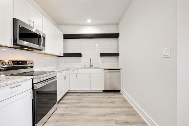 kitchen with tasteful backsplash, white cabinetry, stainless steel appliances, and a sink
