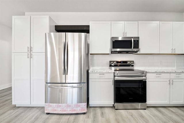 kitchen featuring appliances with stainless steel finishes, light wood-type flooring, and tasteful backsplash