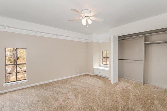 unfurnished bedroom featuring a ceiling fan, baseboards, a closet, and light colored carpet