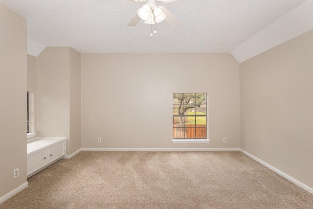 unfurnished bedroom with lofted ceiling, light carpet, baseboards, and a textured ceiling